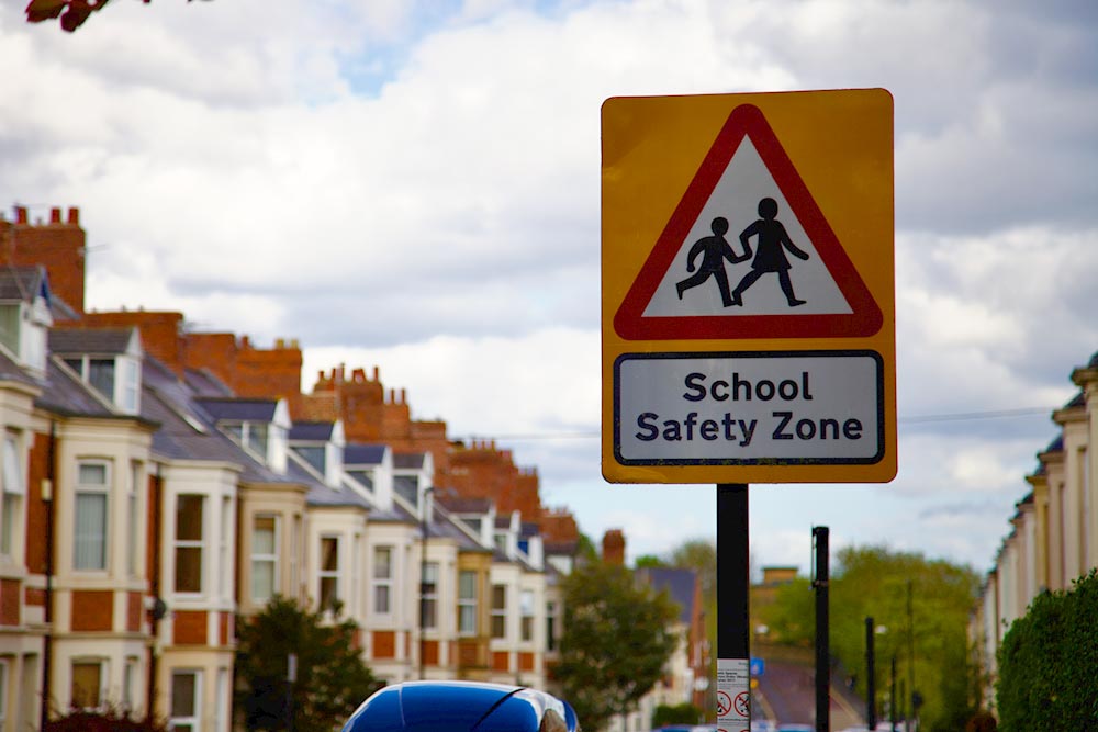 School safety zone sign on street with cars parked